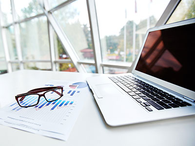 Documents, a computer and a pair of glasses